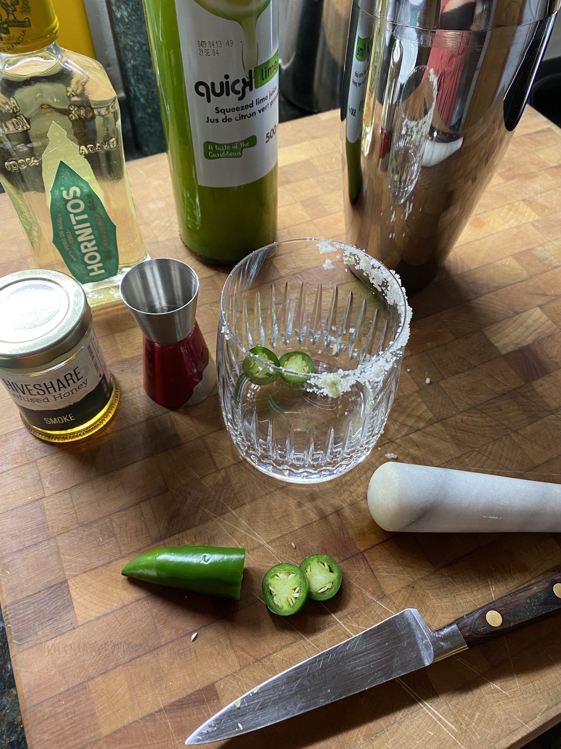 making honey cocktails, jalapenos in the bottom of a rimmed glass